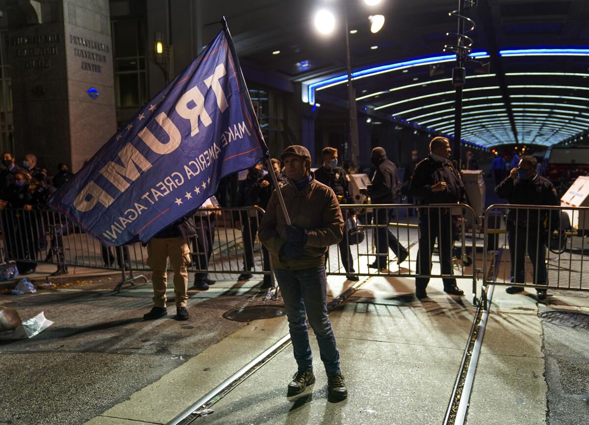 A supporter waves a Trump flag Thursday outside the Pennsylvania Convention Center in Philadelphia as votes are counted.