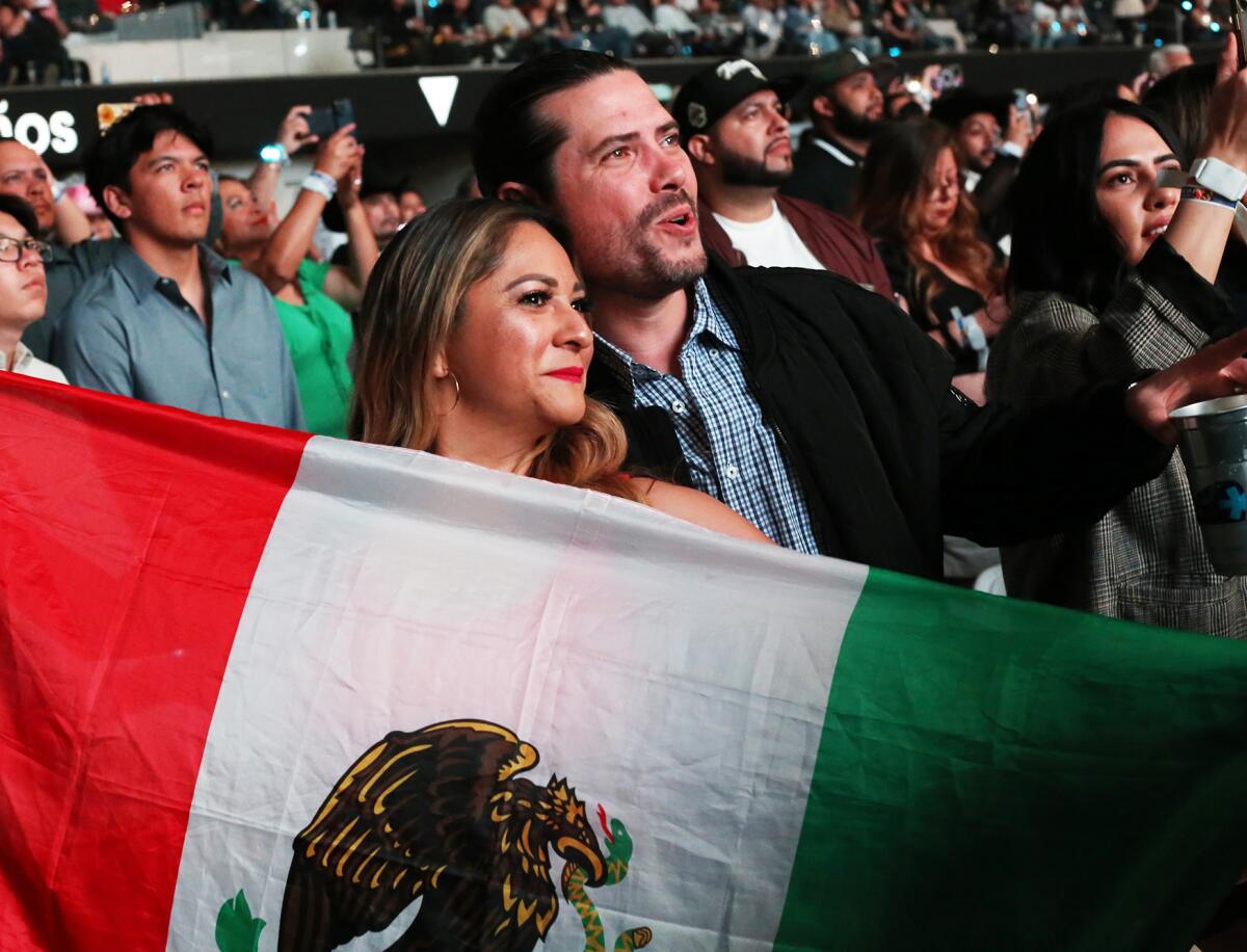Los fanáticos Adrian Arca y su esposa Norma Arca, sostienen con orgullo la bandera 