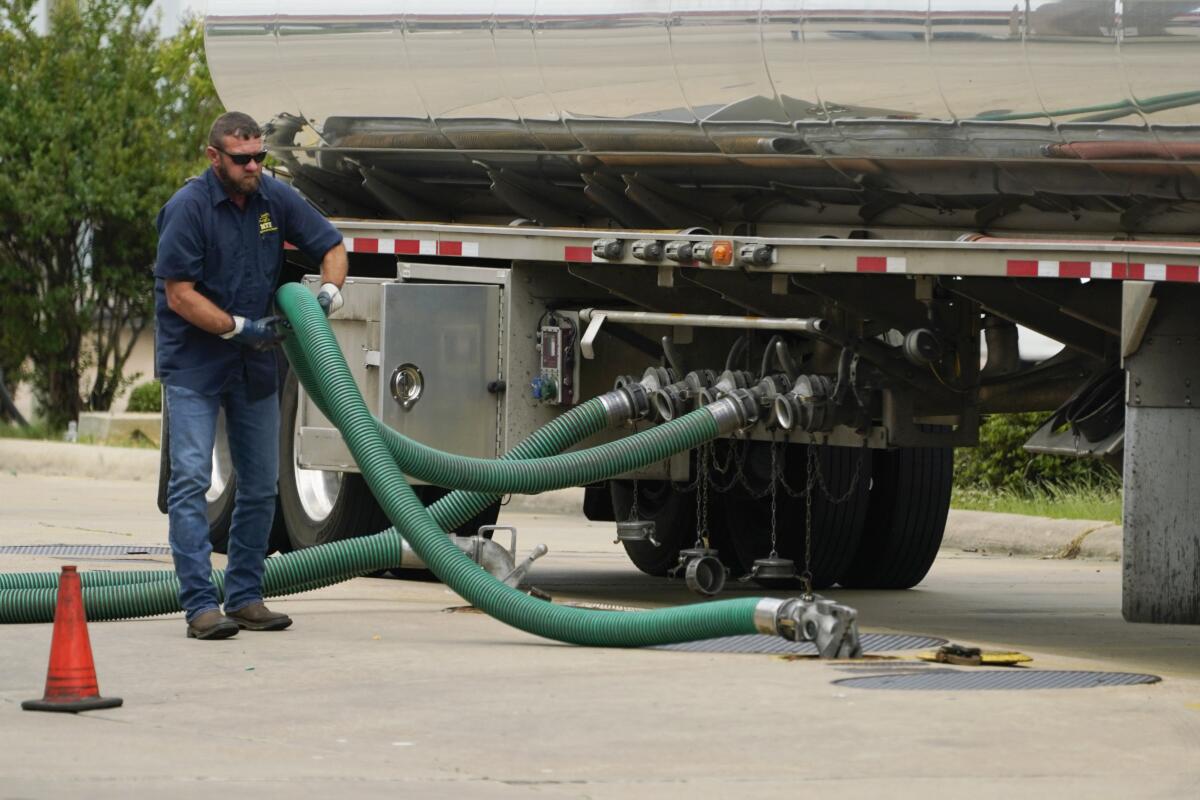 El conductor de un camión cisterna ajusta su manguera a un tanque subterráneo