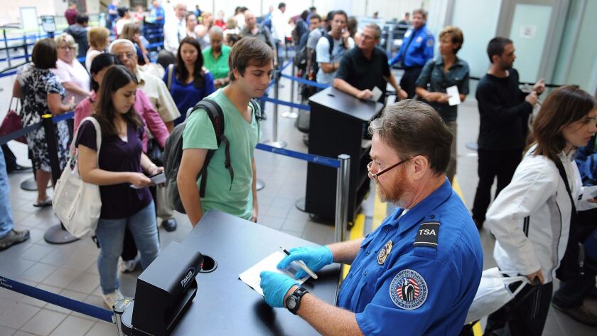 A TSA agent checks the identification of passengers at Los Angeles International Airport. President Trump's budget calls for a hike to the TSA passenger fees.
