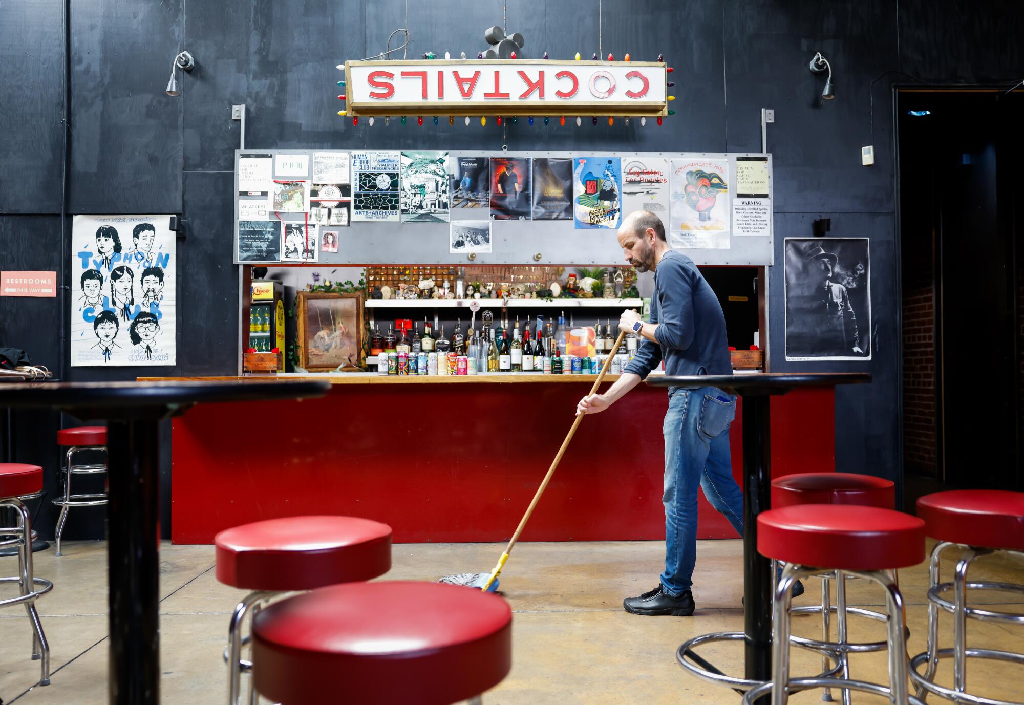 A man sweeps a bar.
