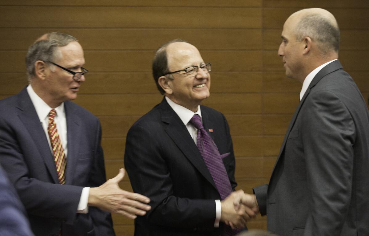 USC Athletic Director Pat Haden, left, and school president Max Nikias, center, congratulate Clay Helton after he was introduced as the permanent head coach of USC football program.