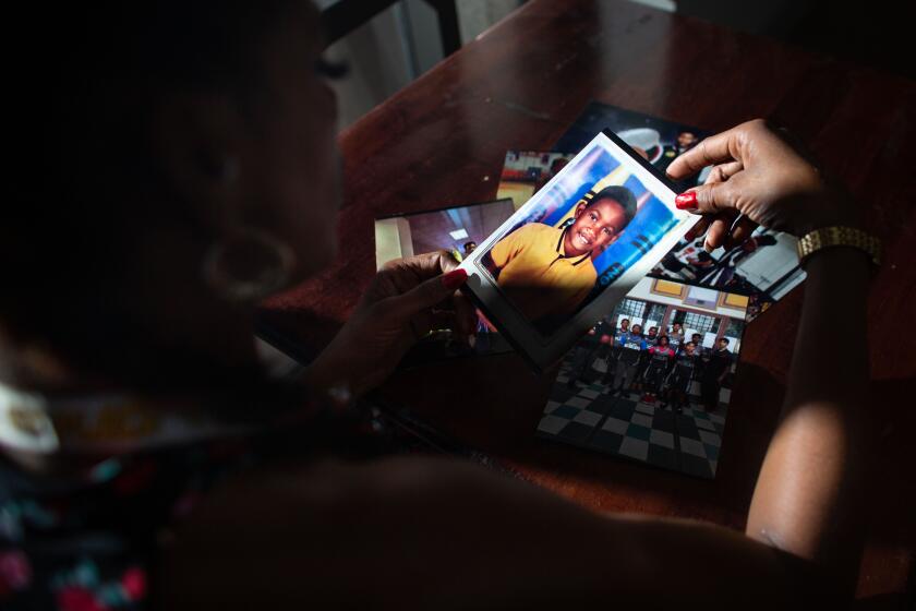 CERRITOS, CA - AUGUST 09: Taloma Miller looks through a stack of photos of her late son Semaj and lingers on a school portrait of Semaj when he was much younger on Sunday, Aug. 9, 2020 in Cerritos, CA. Semaj Miller, a 14 year old basketball player with NBA potential, was shot and killed in Compton (Jason Armond / Los Angeles Times)