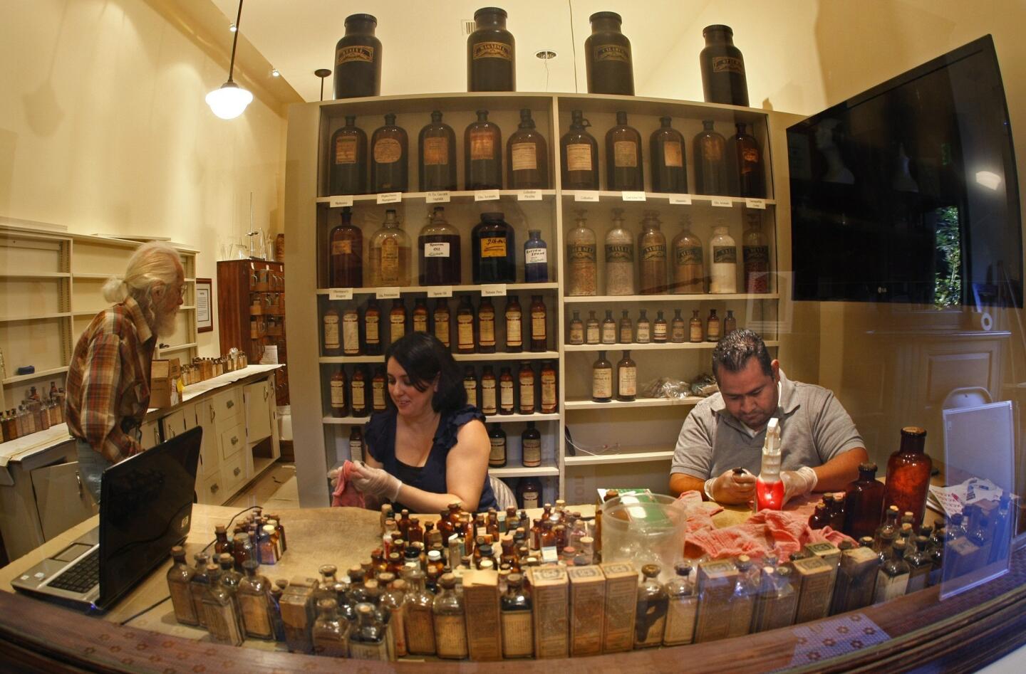 Volunteers Daniele Pineda and her husband Carlo clean decades of dust from early 20th century medicine bottles. Here in the pharmacy of the Colonial Drug museum at Heritage Square in Highland Park, visitors will be able to watch a video about the business once owned and operated by the Simmons family.