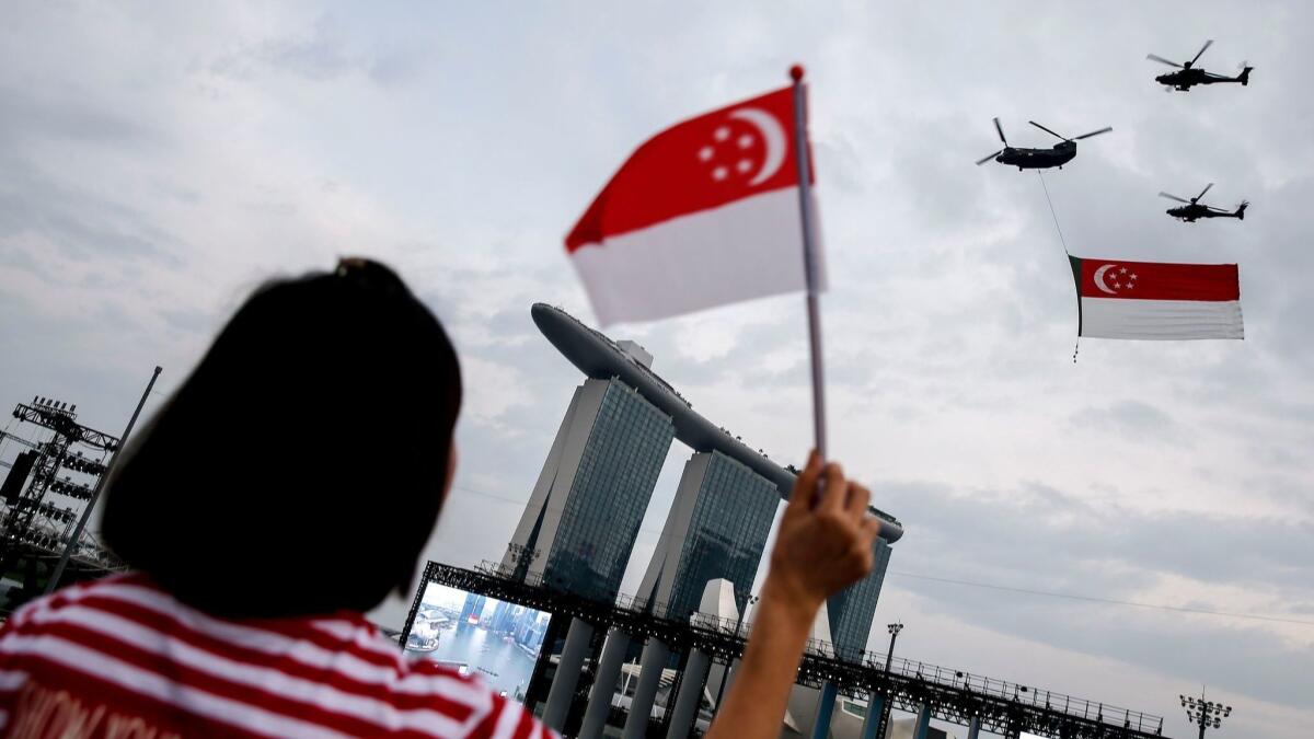 A carries the Singaporean national flag above the Marina Bay Sands, where Singaporeans must pay a $70 entry fee to gamble but foreigners may enter for free.