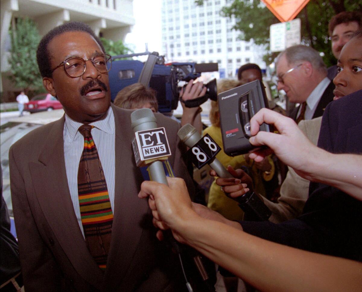 Johnnie Cochran deals with a mass of reporters.